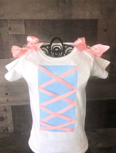 a white shirt with pink bows on the front and blue design on the back, sitting on a mannequin