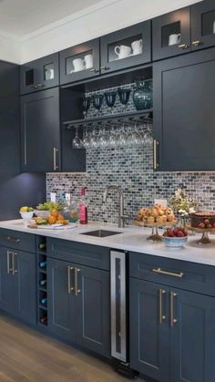 a kitchen filled with lots of counter top space and dark blue cupboards next to a wine glass rack