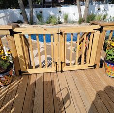 a wooden deck with potted plants on it and a pool in the back ground