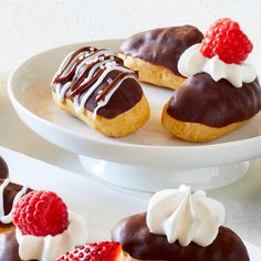 chocolate covered pastries with raspberries and whipped cream on white platter next to other pastries