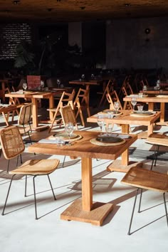 an empty restaurant with wooden tables and wicker chairs on the floor, all set up for dinner