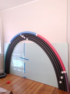 an arch made out of different colored hoses sitting on top of a hard wood floor