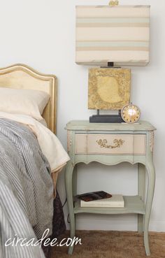 a bed room with a neatly made bed and a night stand on the side table