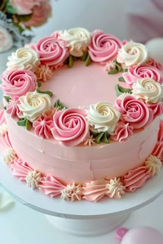 a cake with pink frosting and white flowers on the top is sitting on a table