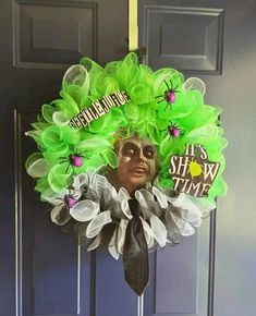 a green wreath with black and white decorations hanging from it's side on a door