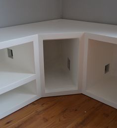 an empty corner shelf in the corner of a room with wood floors and white walls