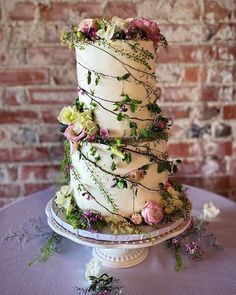 a three tiered cake with flowers and vines on the top is sitting on a table