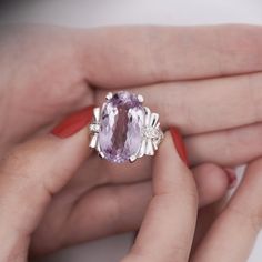 a woman's hand holding an amethoraite and diamond ring