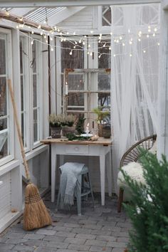 a room filled with lots of white furniture and lights hanging from the ceiling next to a window