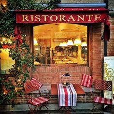 an outdoor cafe with red and white striped chairs, tables and lamps on the outside