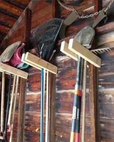 there are many different items hanging on the wall in this room, including brooms and rakes