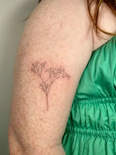 a woman's arm with a small tattoo of flowers on the back of her shoulder