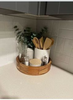 a wooden tray holding utensils and other kitchen items on a white counter top