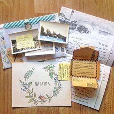 several pieces of paper with stamps and postcards on them sitting on top of a wooden table