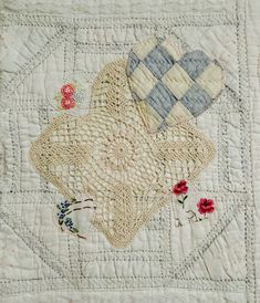 a quilted table runner with hearts and flowers on it, in the middle of an embroidered design