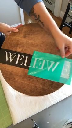 a person standing over a wooden table with a sign on it that says wel