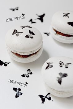 three macaroons with faces drawn on them and butterflies flying around the macaroons