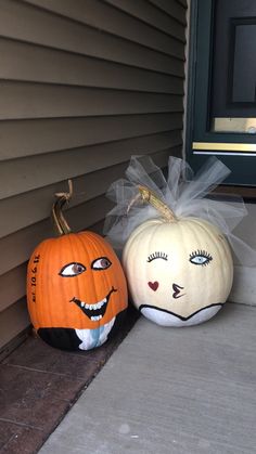 two pumpkins with faces painted on them are sitting on the front porch, ready to be decorated for halloween