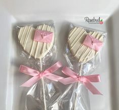 two heart shaped lollipops wrapped in cellophane and tied with pink ribbon