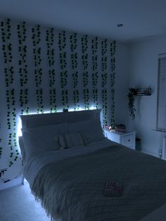 a bed sitting in a bedroom next to a wall with vines on it and lights