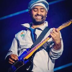 a man playing an electric guitar while wearing a turban on top of his head