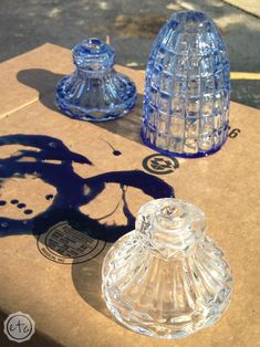 three glass objects sitting on top of a cardboard box next to a shadow of a person