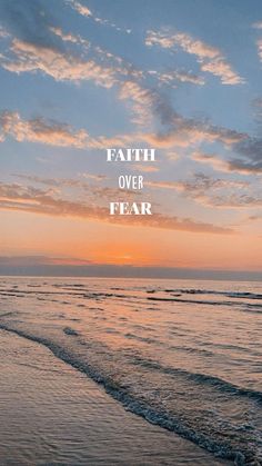 a beach with the words faith over fear in front of an orange sky at sunset