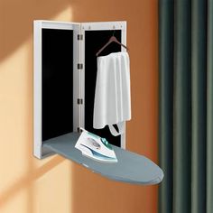 an ironing board is hanging on the wall next to a shirt and towel rack