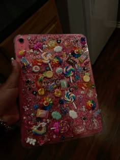 someone is holding up their phone case with many different things on it, including candy and candies