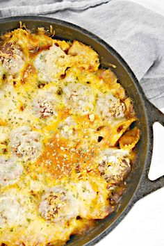 a skillet filled with cheesy food sitting on top of a white table