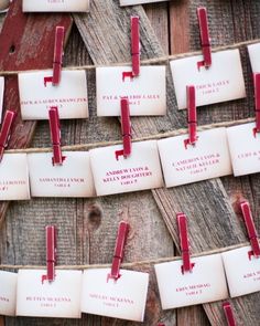 many red and white tags are attached to wooden boards with names on them, hanging from strings