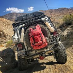 a red backpack is strapped to the back of a jeep