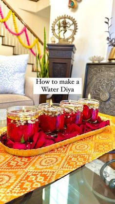 some candles are sitting on a tray with red flowers in it and the words how to make a water diya