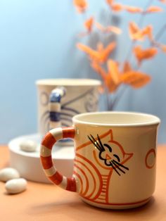 two coffee mugs sitting next to each other on a table