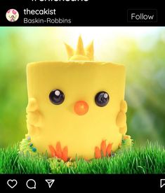 a yellow cake with eyes and a crown on it's head sitting in the grass