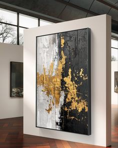 an abstract painting is hanging on the wall next to a wooden floor in front of a large window