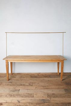 a wooden bench sitting on top of a hard wood floor next to a white wall