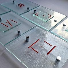 four pieces of glass sitting on top of a white table covered in red and black pins