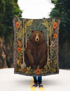 a person holding up a tapestry with a bear on it