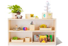 a wooden shelf filled with lots of toys and other items next to a potted plant