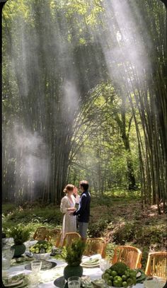 a man and woman standing in front of a bamboo forest with mist coming from the trees