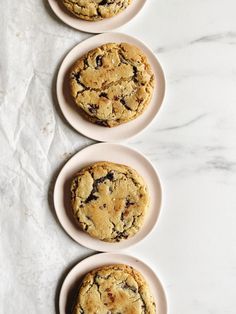 three white plates with cookies on them sitting on a marble counter top next to each other