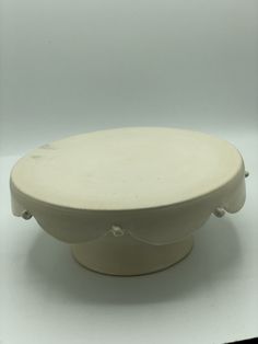 a white plate sitting on top of a white tablecloth covered floor next to a wall