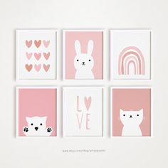 four pink and white art prints with hearts, cats, and rainbows