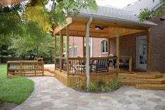 a wooden gazebo sitting on top of a lush green field next to a brick building