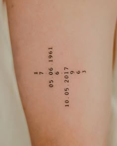 a cross tattoo on the back of a woman's left arm with numbers written in it