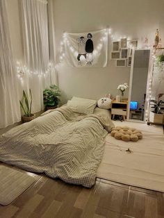 an unmade bed in a room with lights on the wall and wooden flooring