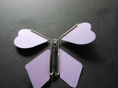 a butterfly made out of purple paper on a black surface with scissors in the middle