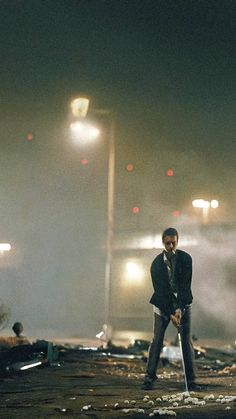 a man standing on top of a street next to a pile of rubble at night