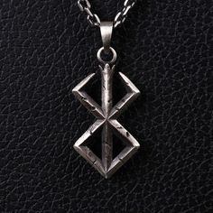 a silver pendant on a black leather surface